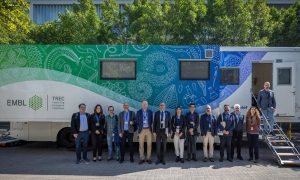 Group picture with a truck-size laboratory on wheels in the background