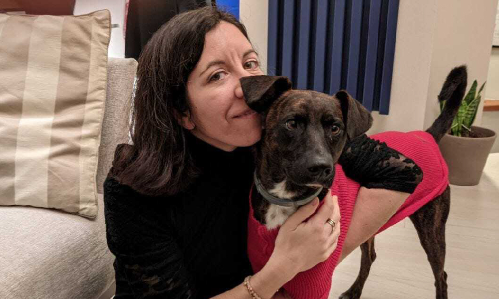 A photo of a woman smiling with a dog.