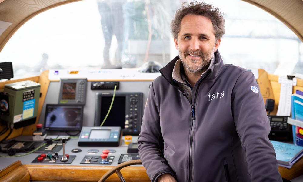 Man standing at the helm of research schooner