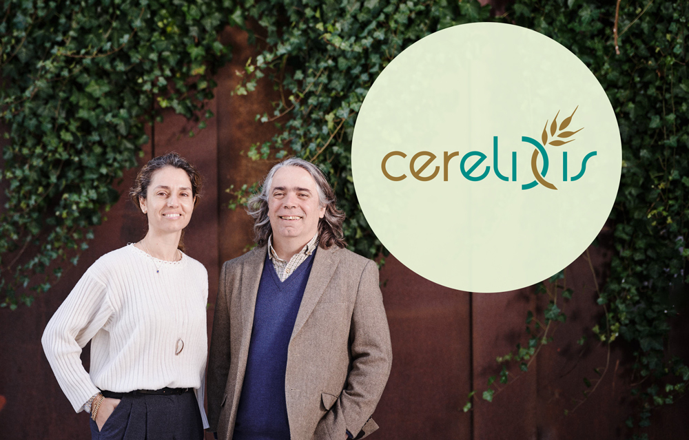 Professional portrait of two startup co-founders standing outdoors in front of a brick building covered with green ivy. On the left, Marianna Vrettou-Schultes, on the right, José Antonio Marquez