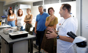 A scientist explaining something to a group of observers inside a laboratory.