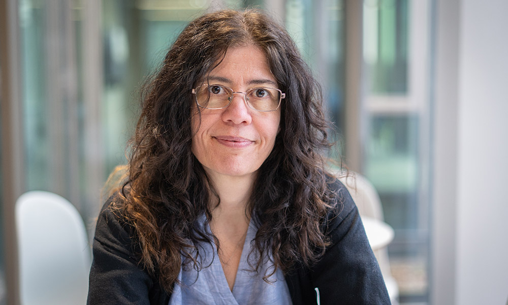 Close-up of smiling woman with glasses and long, dark, wavy hair. Person featured is called Aybuke Kupcu Yoldas. Photo credit: Jeff Dowling.