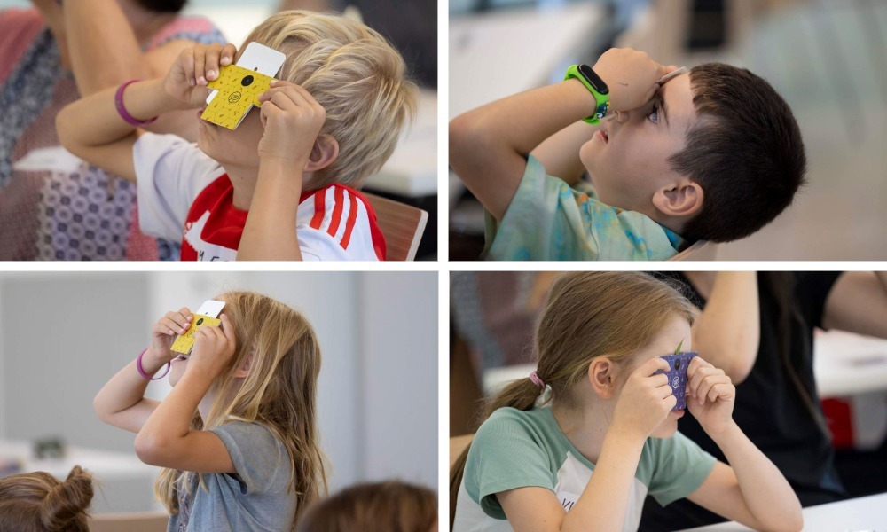 Collage of four images, each showing a child (7-10 years old) looking through a paper microscope (foldscope). 