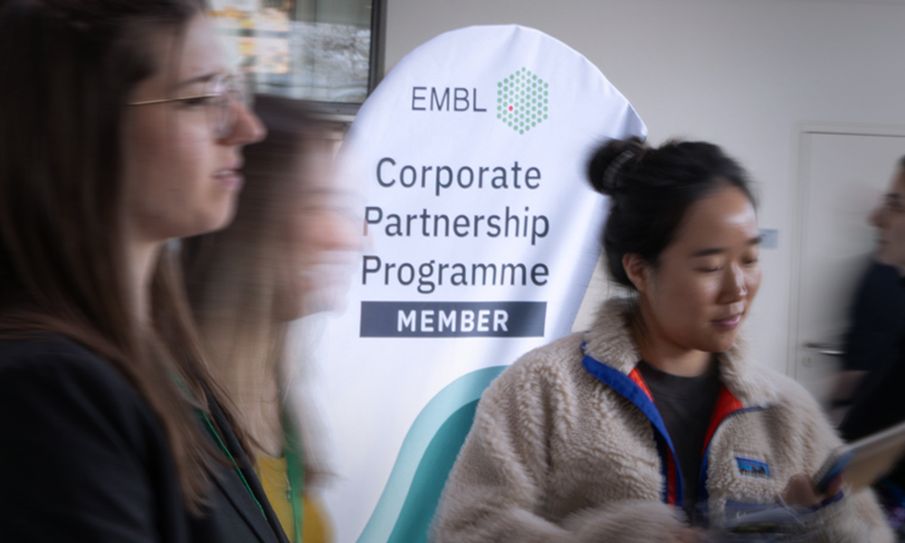 Long exposure photograph of networking, with a sign for the Corporate Partnership Programme in the background