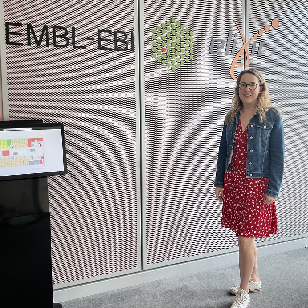 bioinformatician stands in front of EMBL-EBI sign