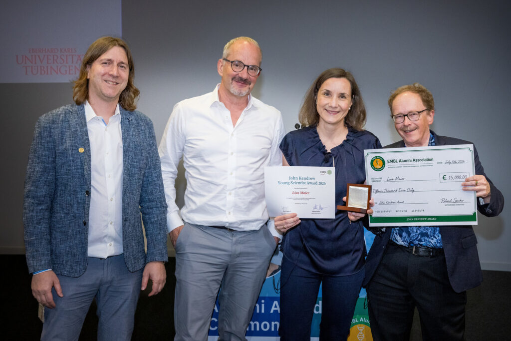 Lisa Maier, EMBL’s 2026 John Kendrew Award recipient, poses for a picture holding her award together with Nassos Typas, Head of Molecular Systems Biology, Tony Hyman, Director General of EMBL, and Pavel Tomancak, EMBL Alumni Association Chair.