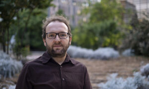 Portrait of Daniel Santos-Olivan, in the background, blurred, there are trees and buildings