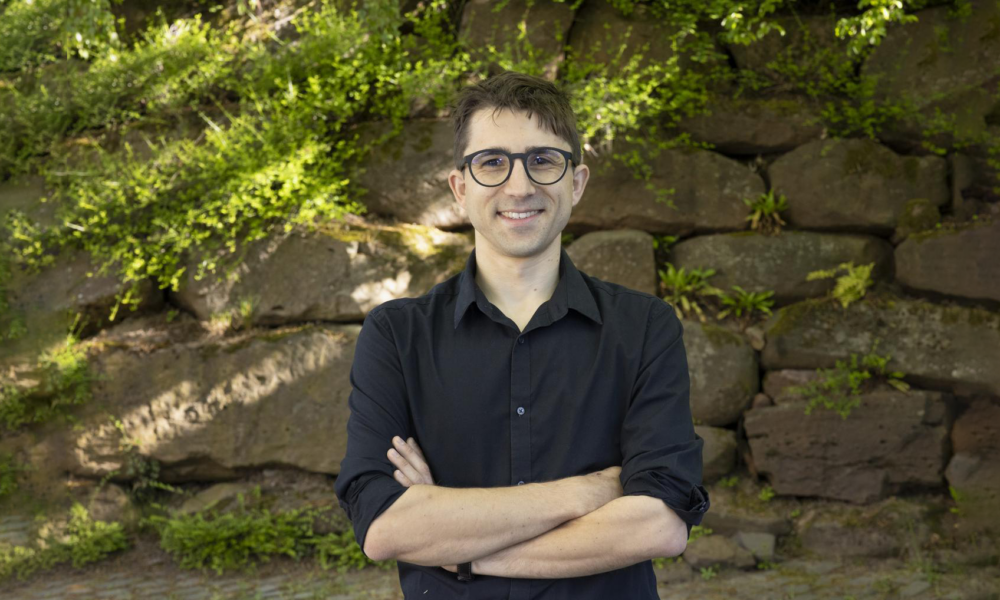 Man standing in front of a wall with plants.