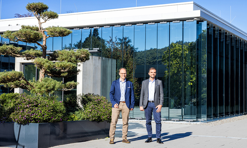 Two male scientists standing outside a building and next to a tree